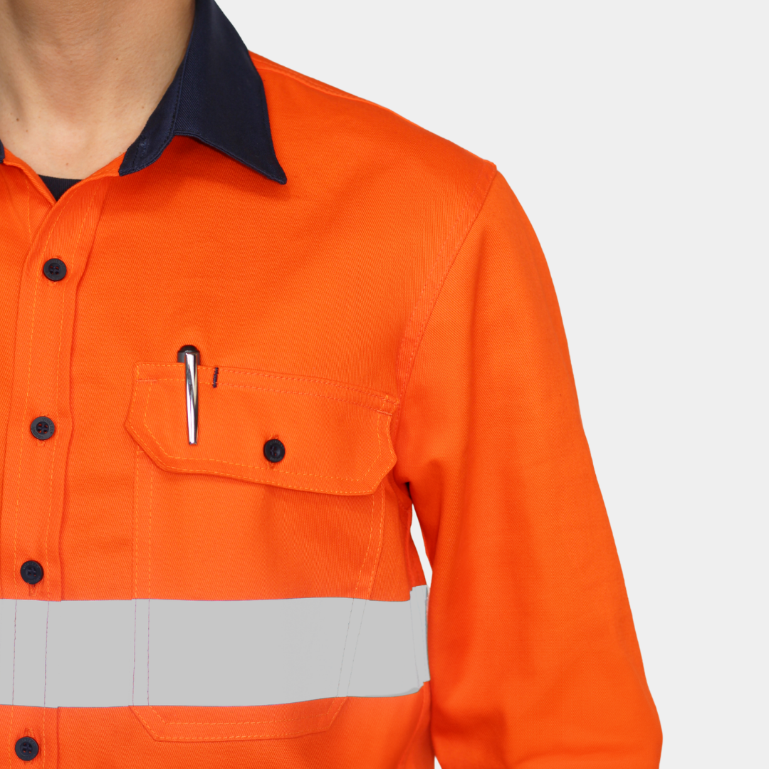 Detalle de bolsillo de pecho de camisa ignífuga FIREWEAR® bicolor naranjo y azul para hombre.